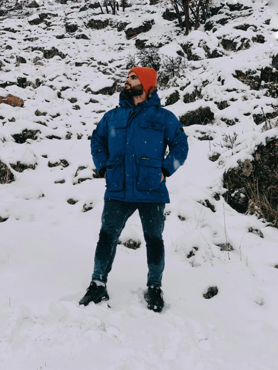 a man standing in the snow next to a mountain