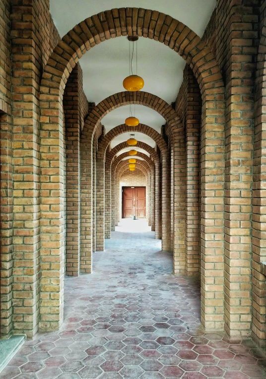 a walkway is lined with arches and brick flooring