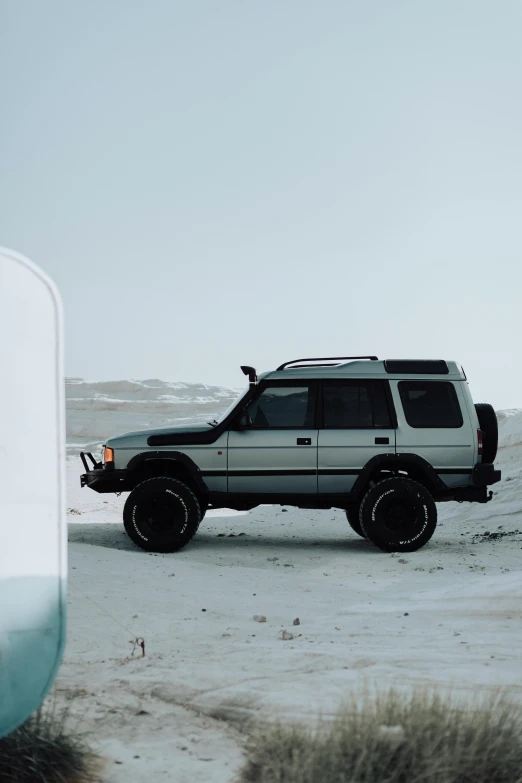 a suv parked on snow covered ground near bushes