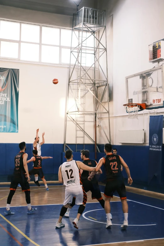 a group of people in the middle of a court playing basketball