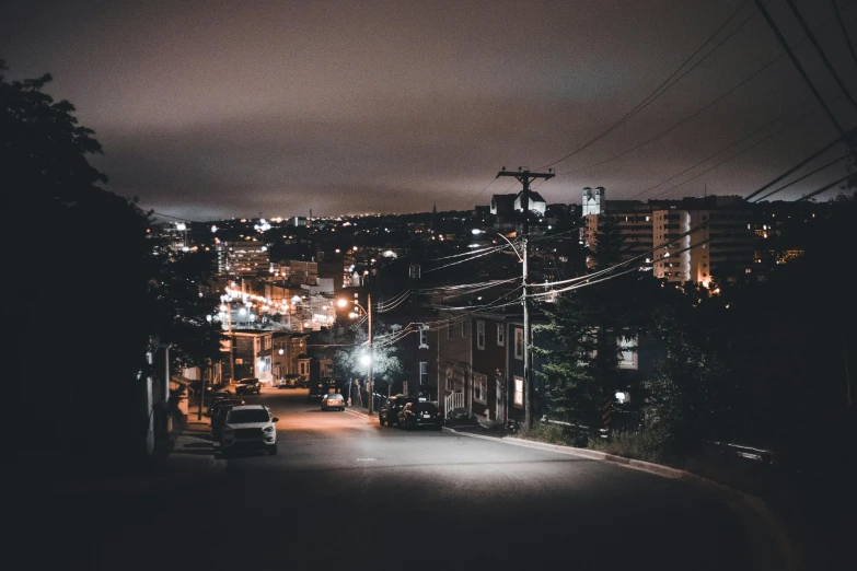 a dark city is lit up at night, with one car parked on the street