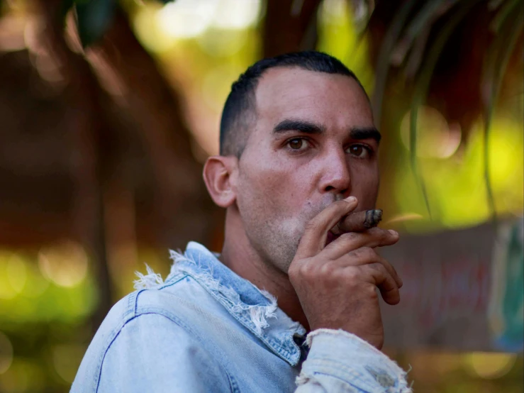 man smokes a cigarette, holding his mouth to his chest