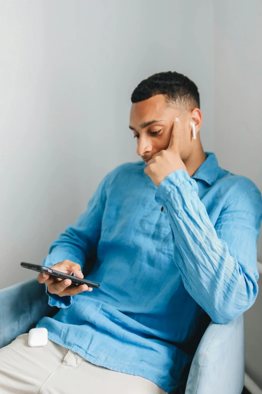 a man sitting in a blue chair with a cellphone