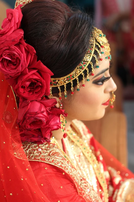 a woman in red and gold is wearing a flowered head piece