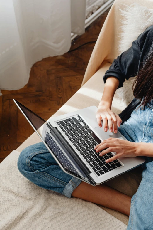 woman using laptop while sitting on couch in living room