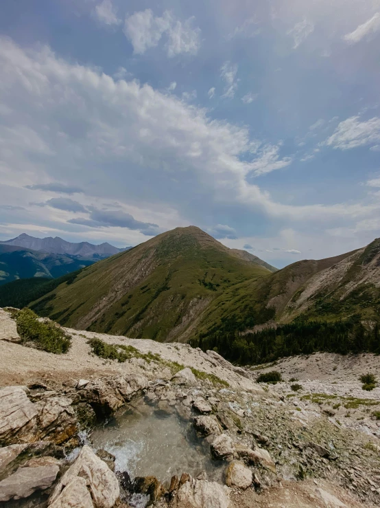 a rocky landscape with a pool of water and mountains in the background