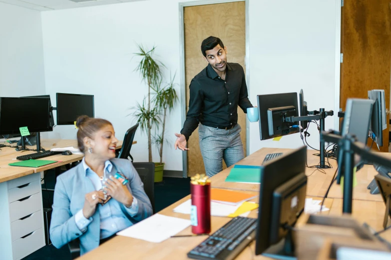 a couple of people at an office with computer screens and computers