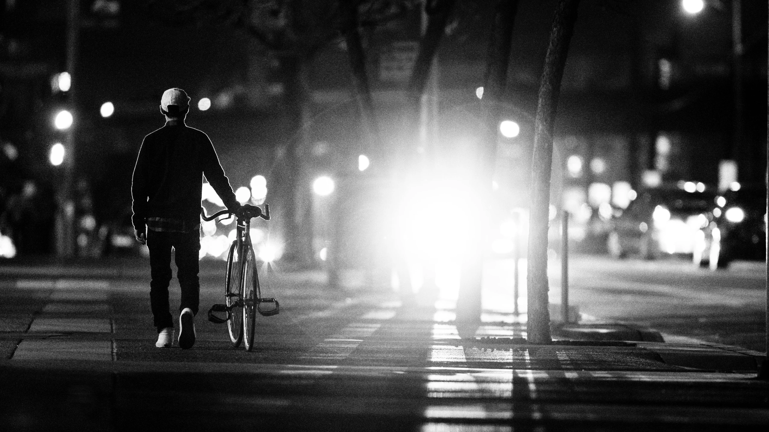 a man with a bicycle waiting for the light to arrive at night