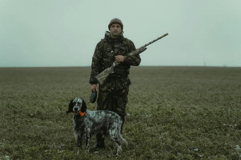 a man holding an old gun and standing next to a dog