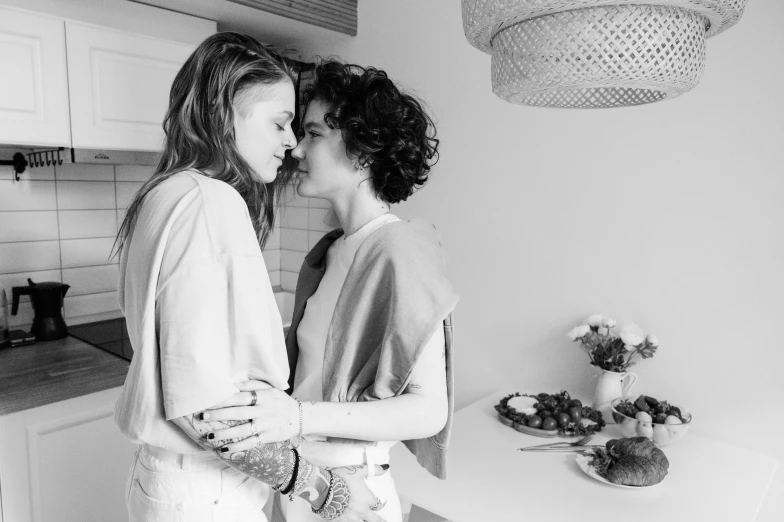 a couple in the kitchen kissing while one woman prepares to eat