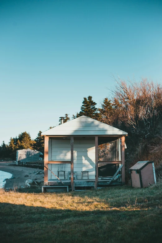 small white cabin near a lake with a few items