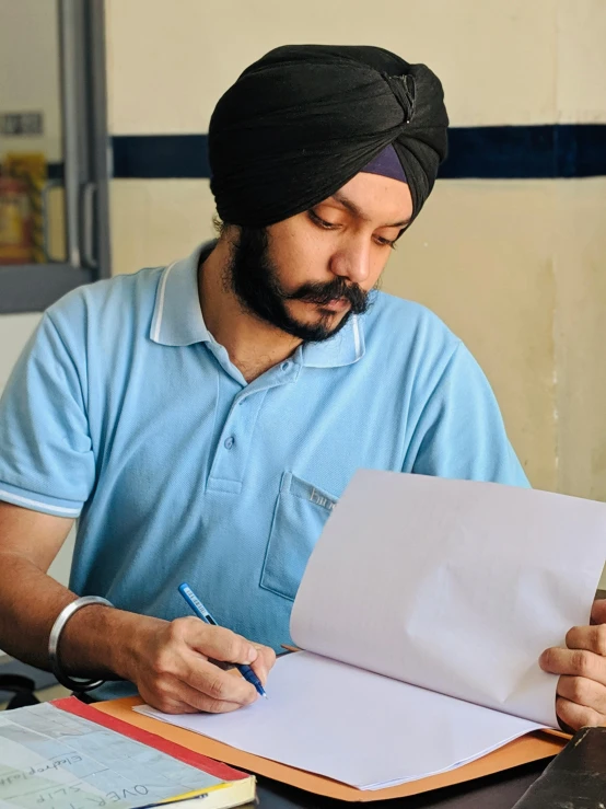 man in turban working with paper on table