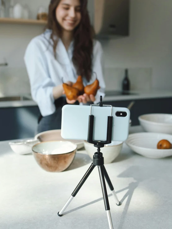 a young woman is holding some food behind a camera tripod