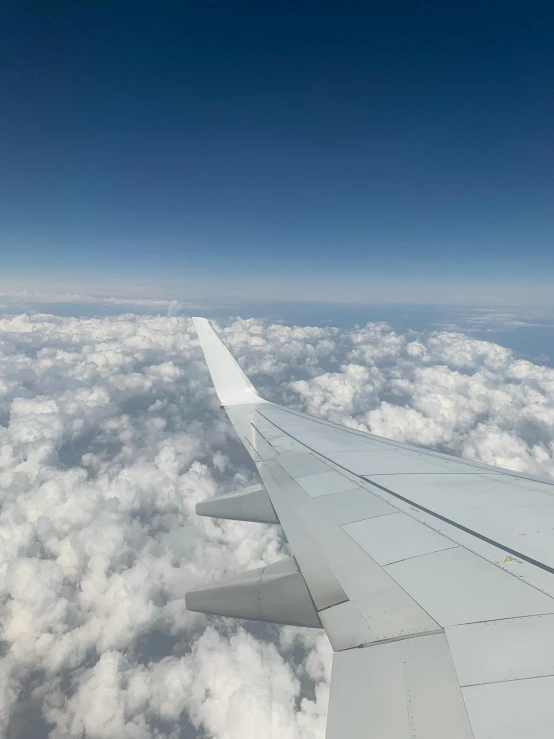 an airplane wing flying above the clouds above