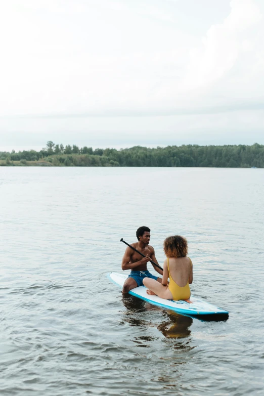 a man and woman riding on top of a blue surfboard