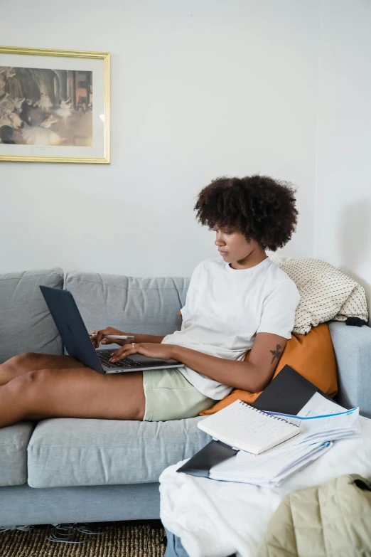 a woman is sitting on a couch using a laptop