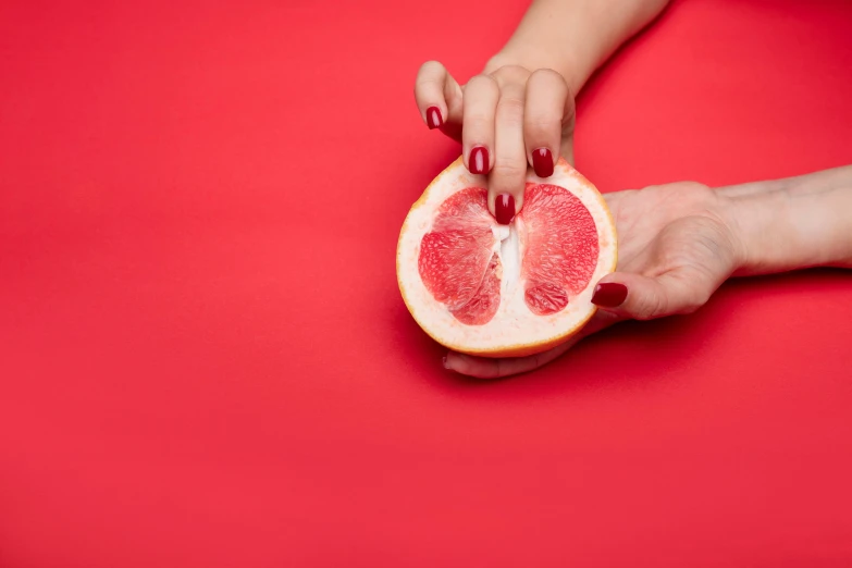 a person holding a half a gfruit with nails