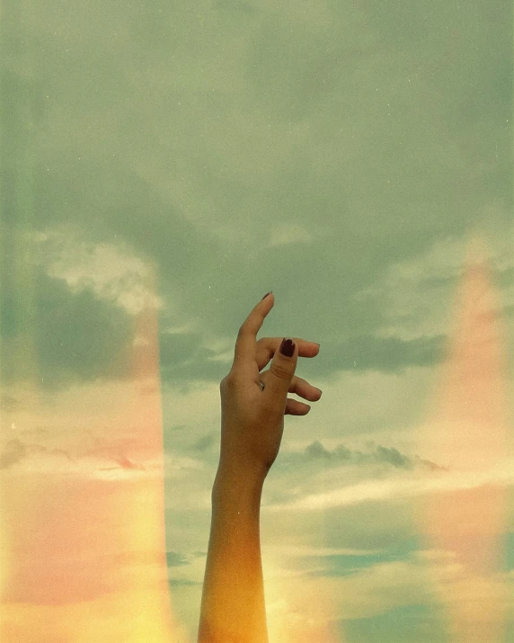 a hand reaching up to an object in the sky