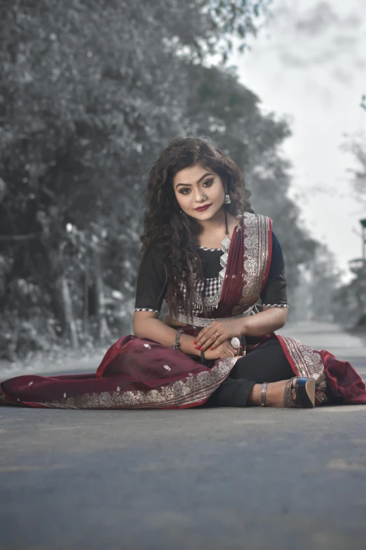 woman sitting down and wearing a maroon, blue and white silk sari