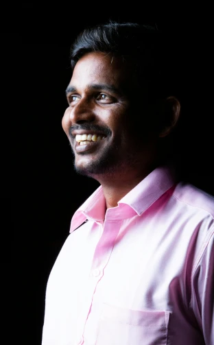 a man is smiling in a pink shirt