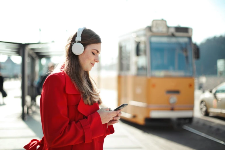 a woman with headphones looks at her cell phone