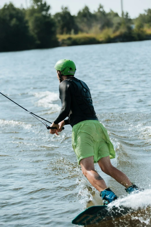 a man in shorts wake boarding on a lake