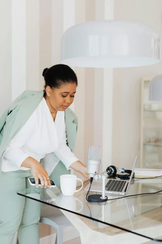 a woman looking at a phone and holding a laptop