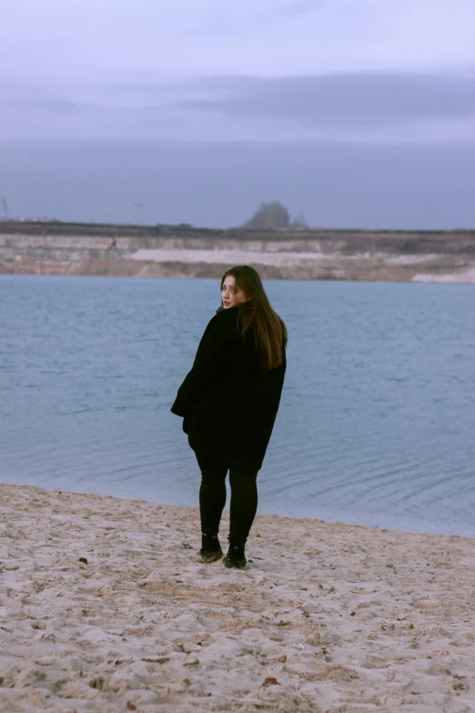 a woman walking along the shore in winter