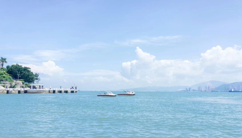 two boats out on the water near a pier