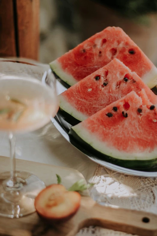 three slices of watermelon on a plate with a glass of wine