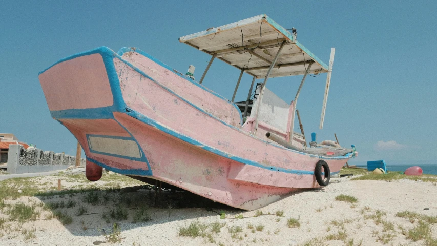 a pink boat on top of a sandy beach