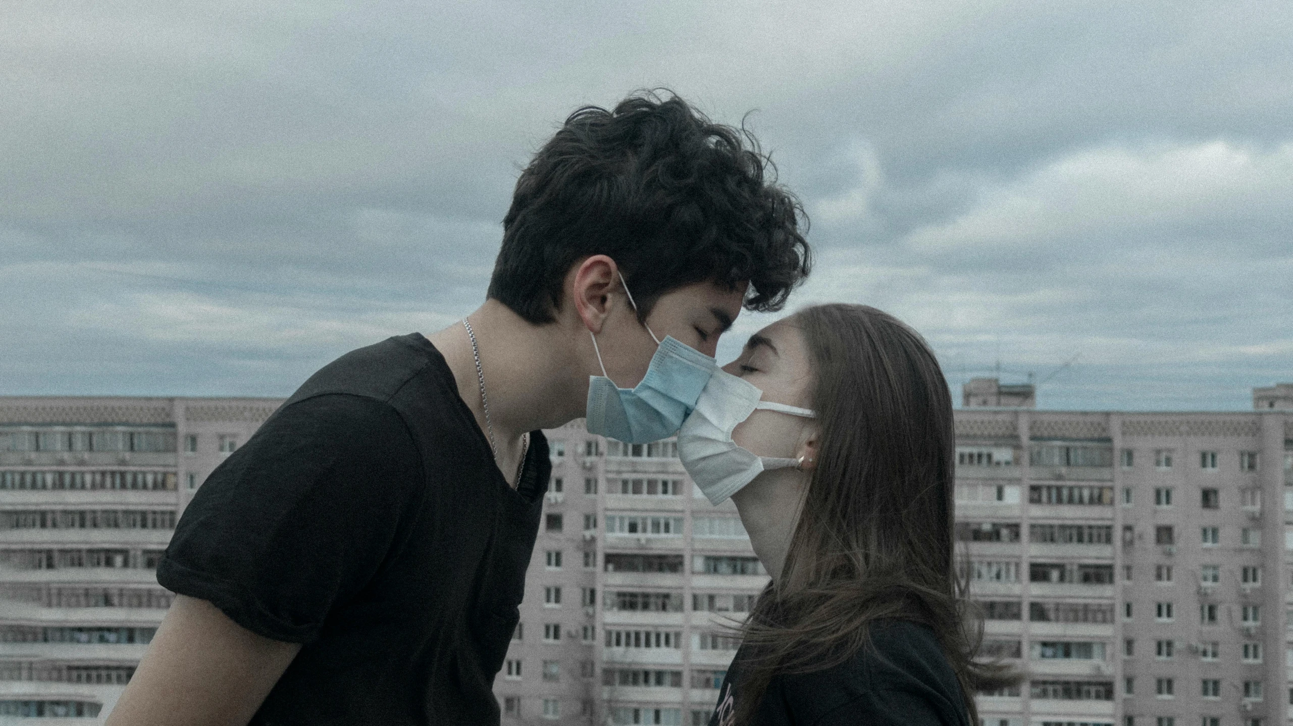 two people on the rooftop with city buildings in the background