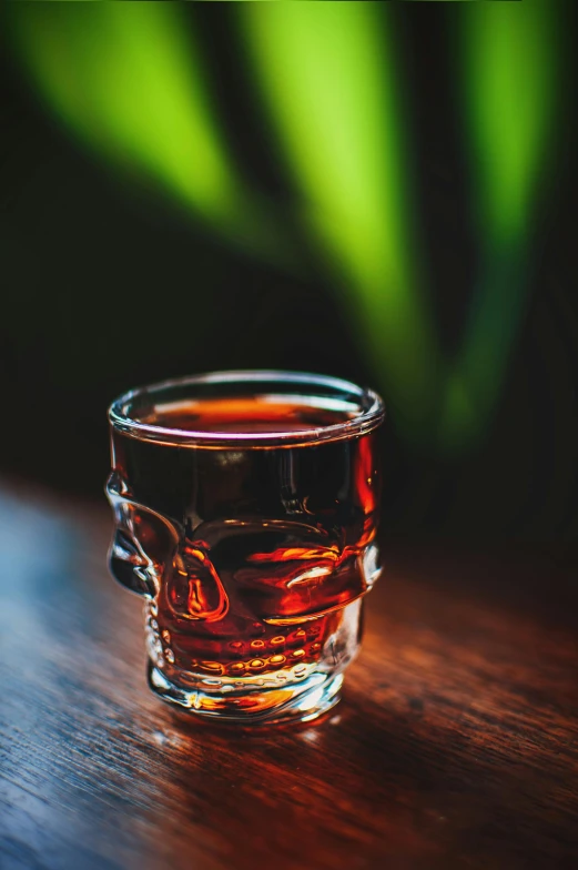 a glass of liquid on top of a wooden table