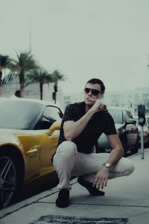 a man sitting in front of a parked sports car