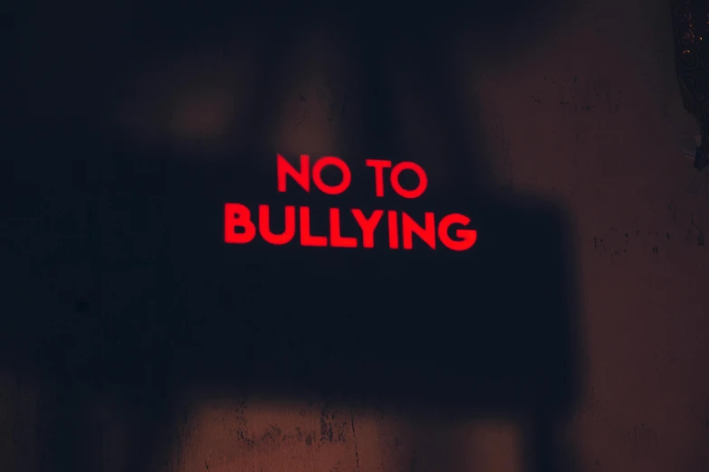 the red neon sign says no to bullying on the wall