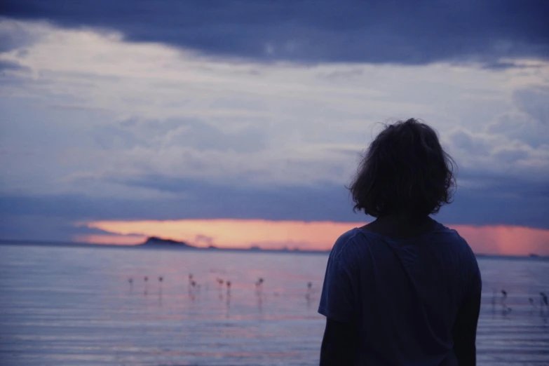 a man standing on the beach looking out to sea