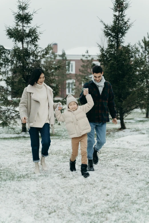 a young family walks through the snow in a park