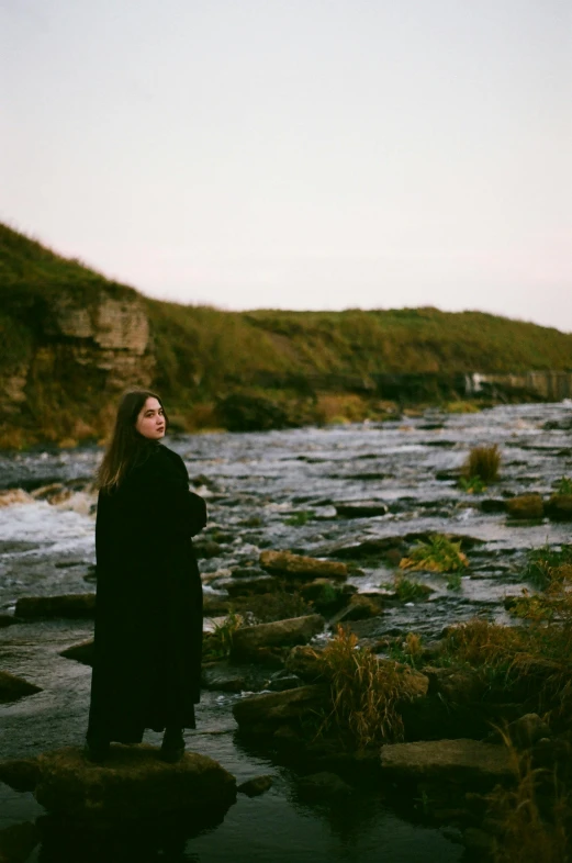 a woman is posing for a pograph near the water