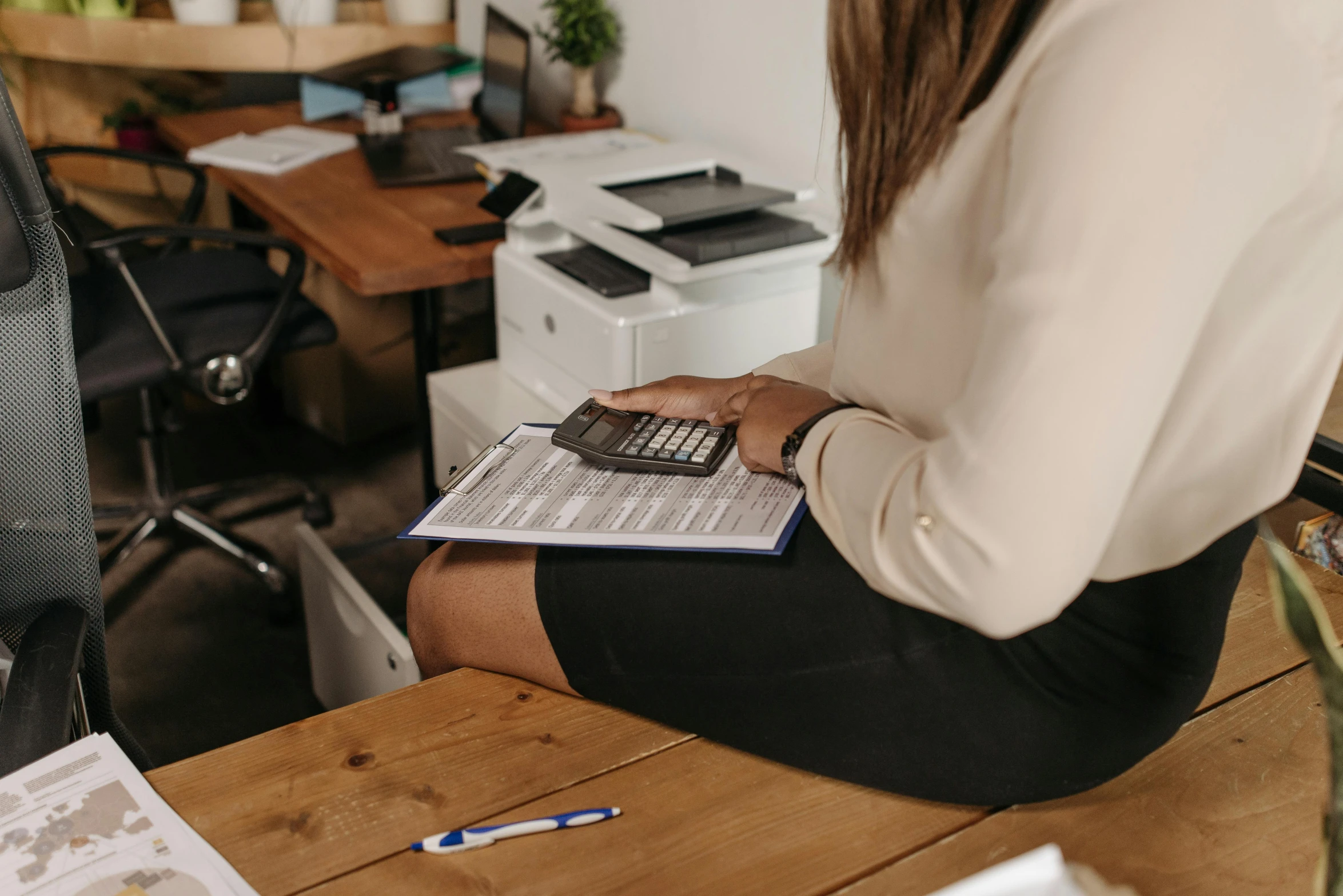 a person holding a calculator while sitting at a desk