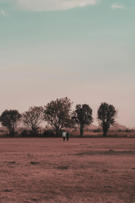 two people walking in a field while the sky is dark