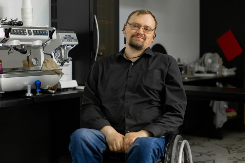 a man sitting in a wheelchair in front of a coffee machine