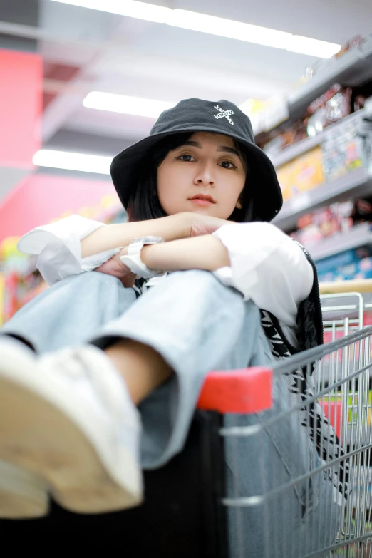 a person with a hat sitting in a grocery store cart