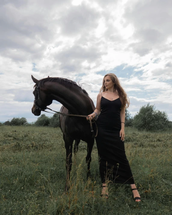 a woman is standing in a field by a horse