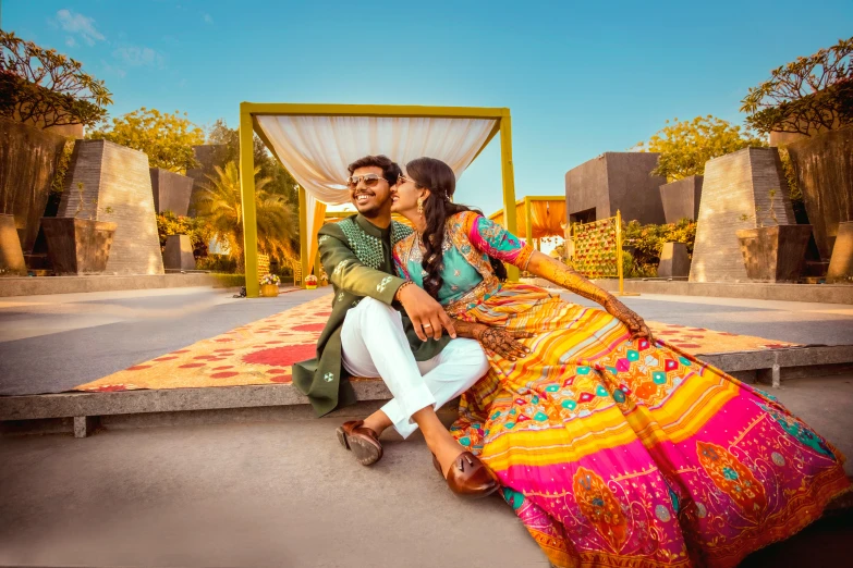 a bride and groom sitting outside near a stage