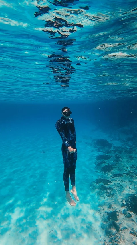 a person in black wet suit snorzes about to enter water