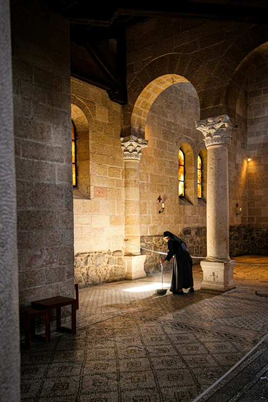 a person kneeling in an old room with brick walls and arches