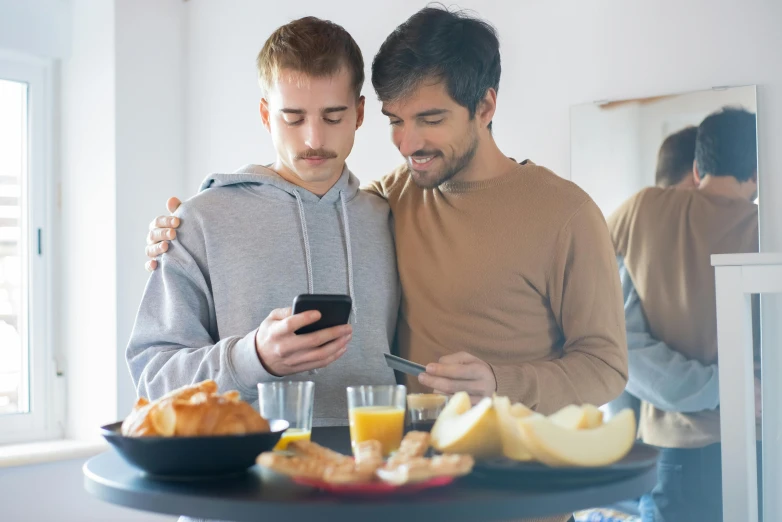 two men standing next to each other near food on a tray