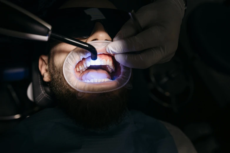 a person getting their teeth done with a light