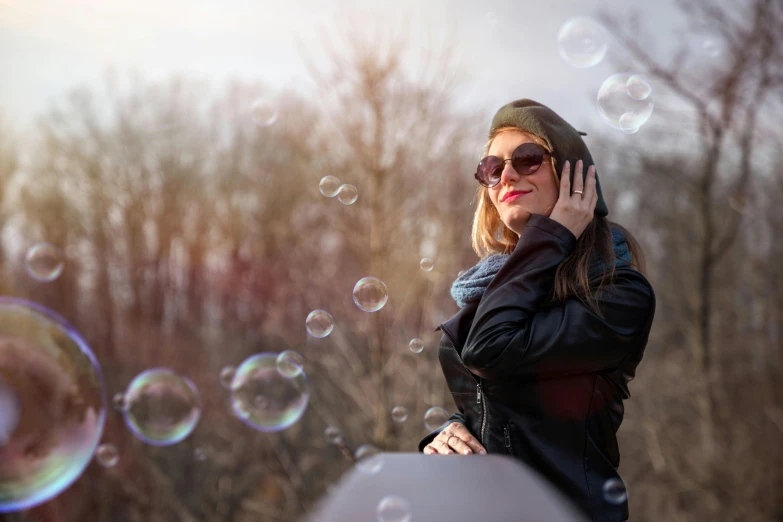 woman in winter gear with cell phone and soap bubbles floating from her ear