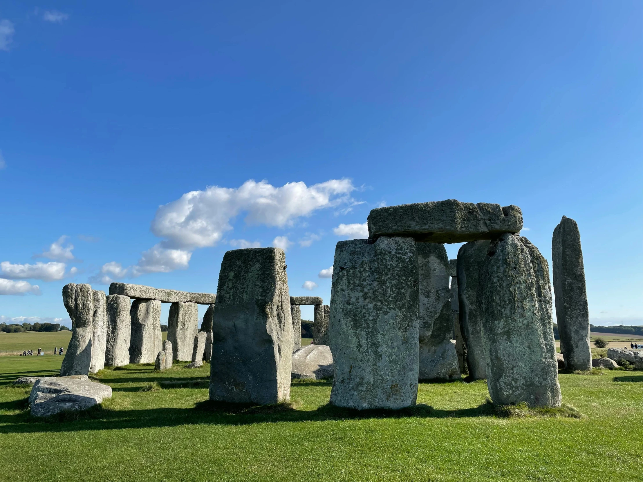 large stonehenges sit in the grass on a bright day